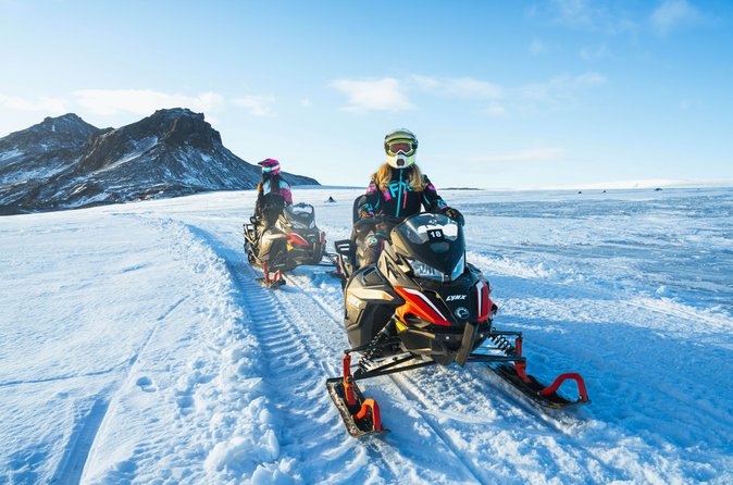 Snowmobile riders wearing protective winter gear on Langjökull Glacier